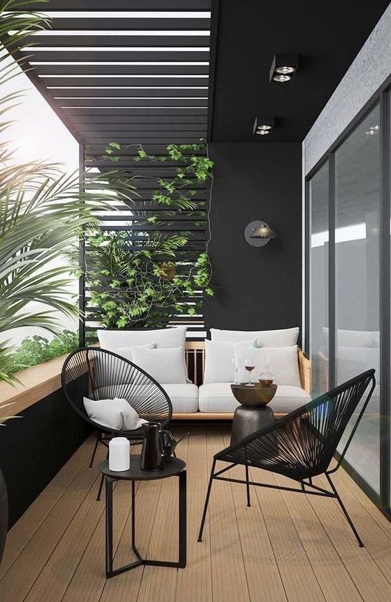 a small terrace with black wicker chairs, a comfy sofa, climbing greenery and a tiny coffee table