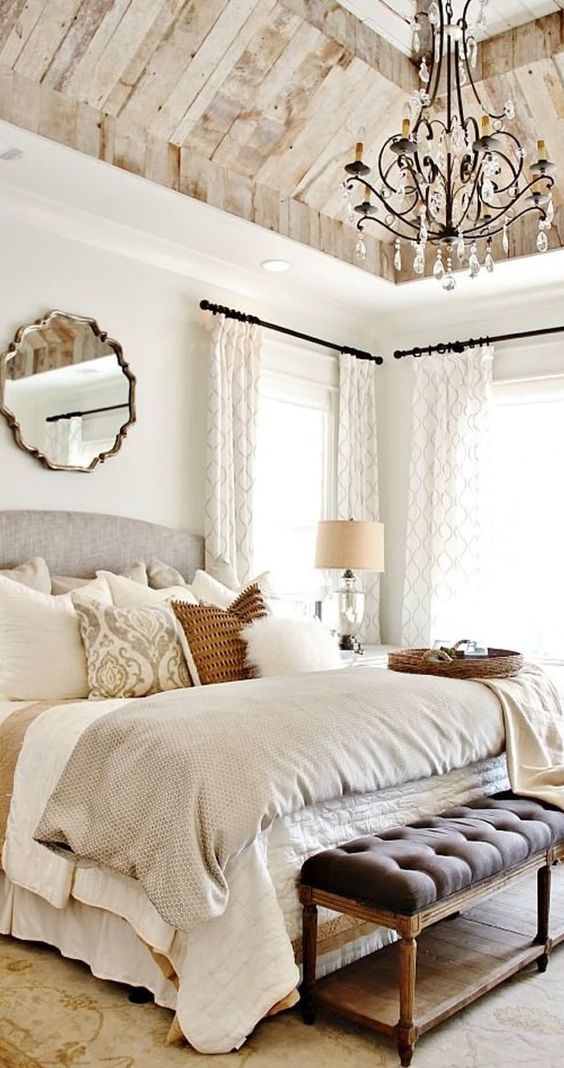 a vintage glam bedroom with a crystal chandelier, a mirror, printed textilesand lamps and candles