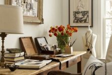 a vintage home office with a stained desk, a stained chair with neutral upholstery, some artwork and a vintage memo board