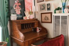 a vintage working nook with a gallery wall, a small stained bureau desk, a stained chair and some potted greenery