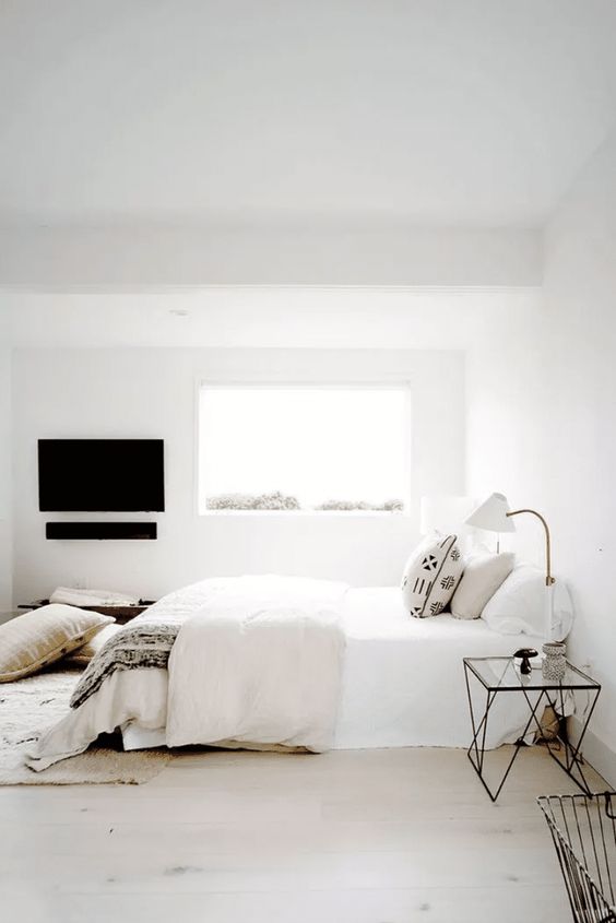 a welcoming zen bedroom with a bed, lightweight glass nightstands, sconces, pillows and blankets