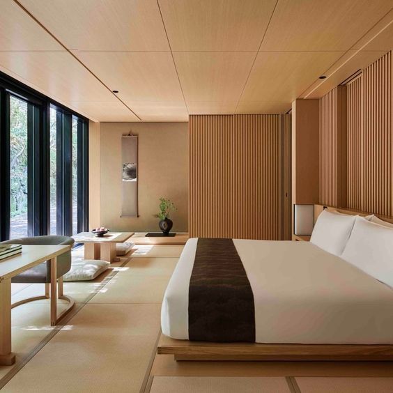 a zen bedroom with low wooden furniture, wooden screens, a glazed wall and some statement plants and artworks
