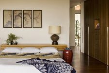 an Asian zen bedroom with a bed on the floor, a floating console at the head, a gallery wall and bright bedding