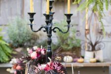 a bold and refined Halloween tablescape with gold cutlery and chargers, masks, deep toned blooms and feathers and candles