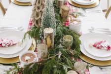 a bright winter table with a red plaid runner, napkins, birch branches, faux Christmas trees and an evergreen runner