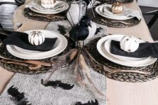 a chic black and white Halloween tablescape with black crows, bats, napkins, painted pumpkins, woven placemats and wheat