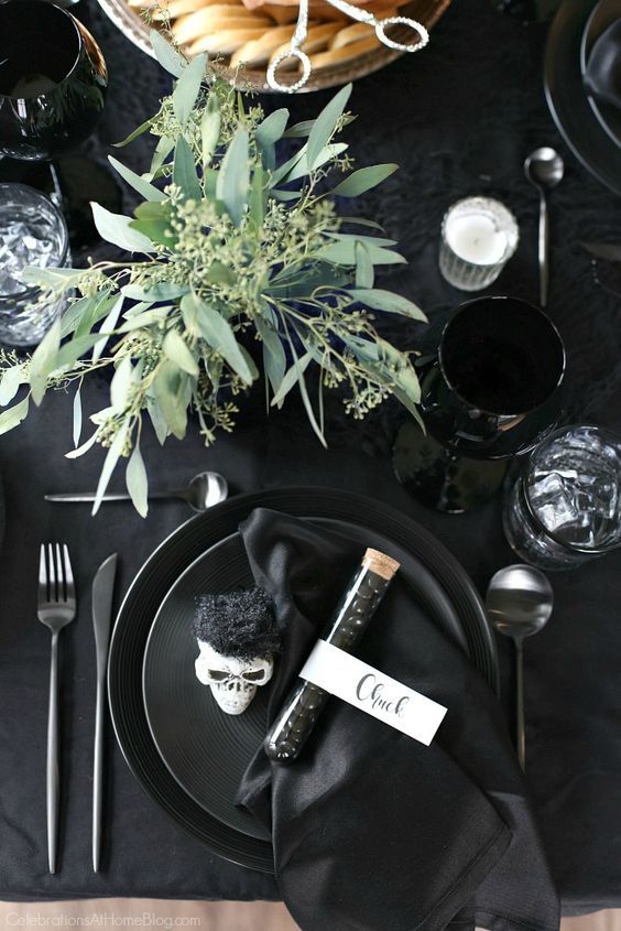 a classy modern Halloween tablescape with all things black, skulls, candies, eucalyptus, candles and matte cutlery