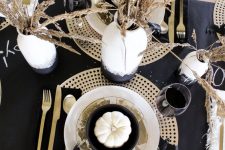 a modern glam Halloween table setting with gold chargers, cutlery, a black runner and watercolor vases with wheat