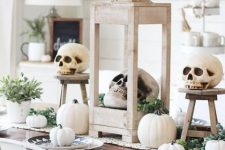 a neutral rustic Halloween tablescape with a woven runner, white pumpkins and skulls, greenery and succulents