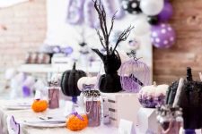 a pastel modern Halloween tablescape with black, watercolor and wire pumpkins, lavender lemonade and cutlery, candies and branches