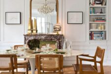 a pretty French dining room with built-in shelves, a fireplace clad with marble, an oval table and stained chairs