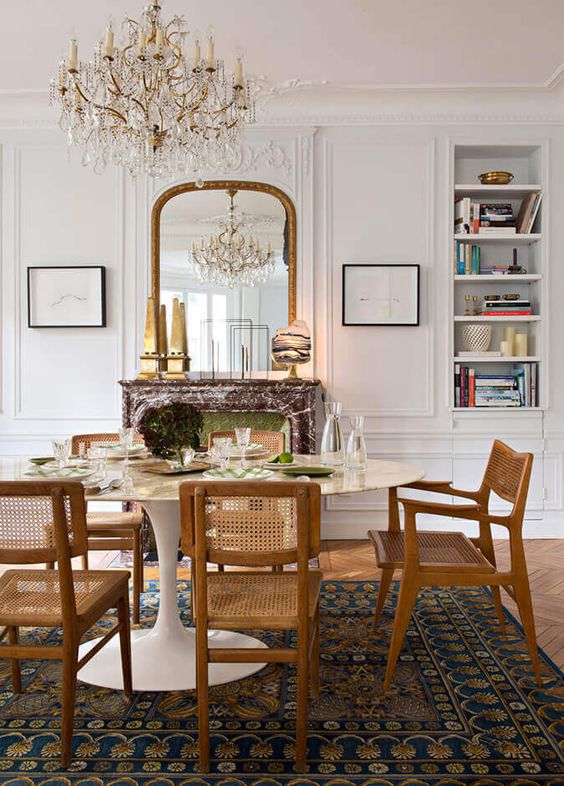 A pretty French dining room with built in shelves, a fireplace clad with marble, an oval table and stained chairs