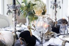 a refined black and white Halloween tablescape with velvet pumpkins, black candles, white blooms, printed plates