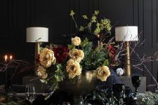 a sophisticated Halloween tablescape with yellow and burgundy blooms, eucalyptus, gold chargers and cutlery, candles