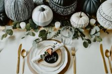 a stylish modern Halloween tablescape with grey, black and white pumpkins, eucalyptus, gold cutlery and chargers