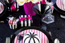 a super bright modern Halloween tablescape in black, white and hot pink, white roses, pink plates, napkins and other detailing
