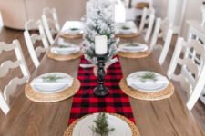 a very simple and cozy winter table with a plaid runner, woven palcemats, evergreens and a snowy Christmas tree