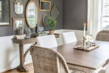 a vintage French farmhouse dining area with wicker and upholstered chairs, a wooden table and a gallery wall with frames and mirrors