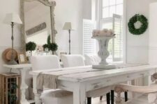 a vintage dining space with neutral and pastel furniture, blooms and greenery, a statement crystal chandelier and a refined mirror