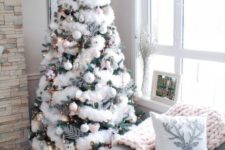 a Christmas tree decorated with white and silver ornaments, lights and fluffy fur garlands plus a large silver topper