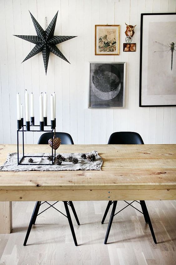 a black modenr candelabra with pinecones and a blakc star on the wall for a Nordic feel