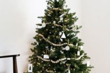 a chic Christmas tree with white ornaments and wooden bead garlands, lights and a faux fur skirt