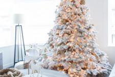 a flocked Christmas tree with matching white and silver ornaments and lights