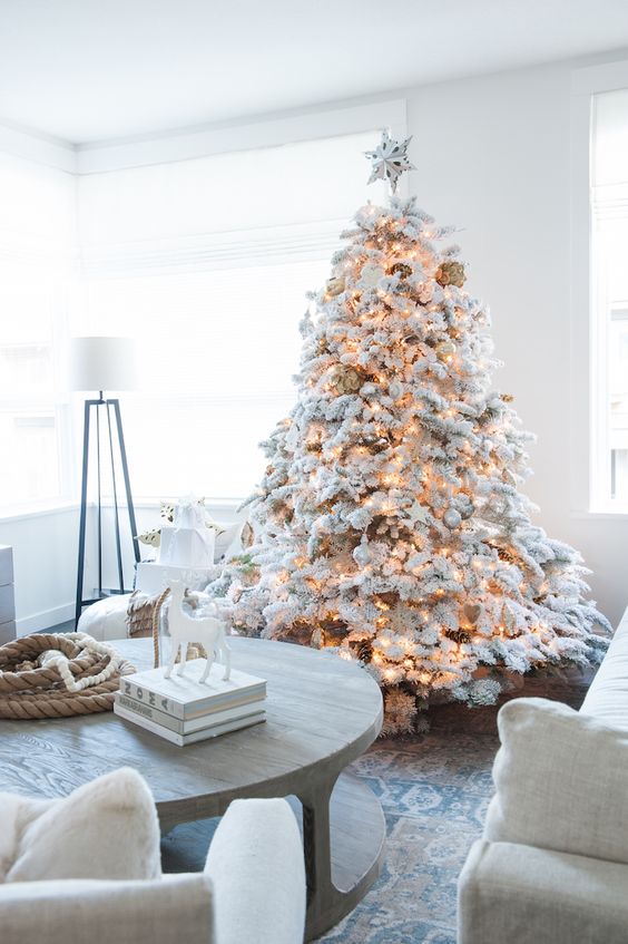 a flocked Christmas tree with matching white and silver ornaments and lights