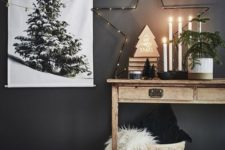 a lit up star, a Christmas tree artwork, a mini tree in a pot and a basket with pillows