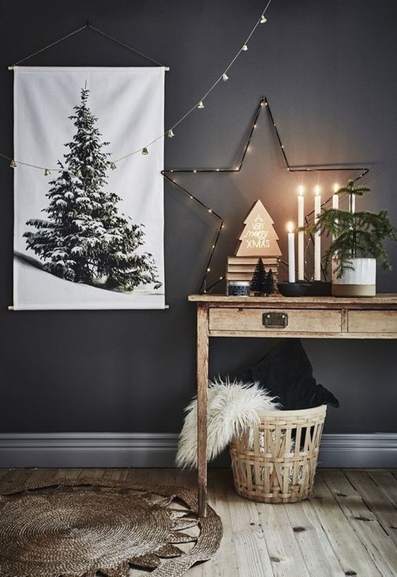 a lit up star, a Christmas tree artwork, a mini tree in a pot and a basket with pillows