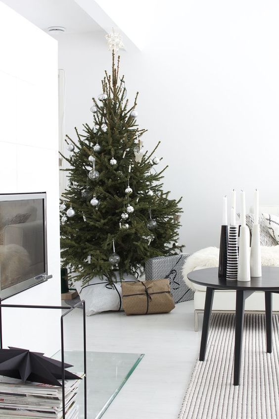 a minimalist Christmas tree with sheer and metallic ornaments and white and black candleholders