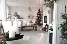 a monochromatic Scandi space with evergreens, white ornaments, candles and candle lanterns looks very modern