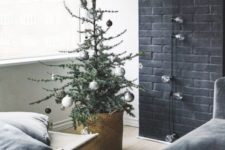 a small Christmas tree with metallic and black ornaments in a basket for a Nordic feel