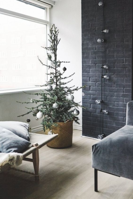 a small Christmas tree with metallic and black ornaments in a basket for a Nordic feel