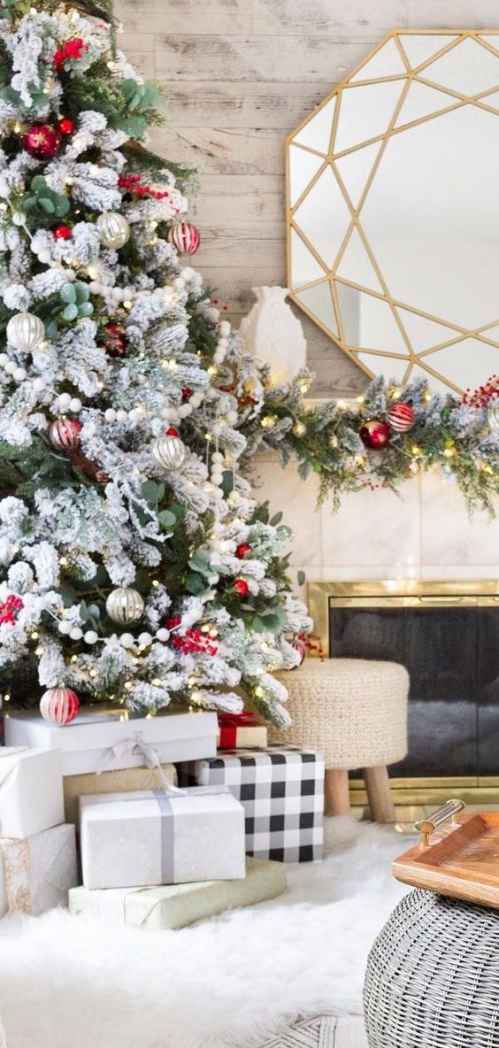 a snowy Christmas tree decorated with red and silver ornaments and fresh greenery for a bold festive look