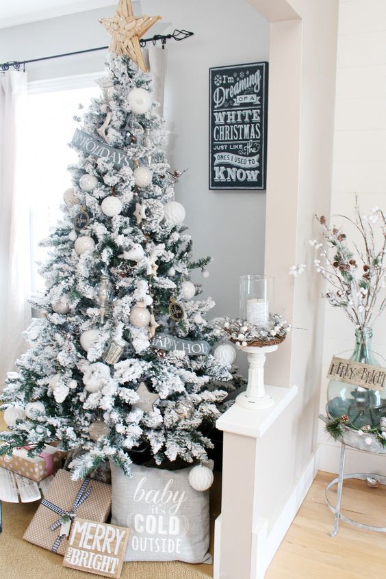 a snowy Christmas tree with metallic and white ornaments, stars, signs, a large star on top