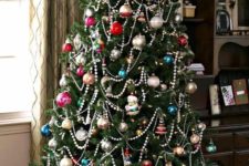 a Christmas tree with colorful vintage ornaments and beaded garlands plus lights for a chic and bold look