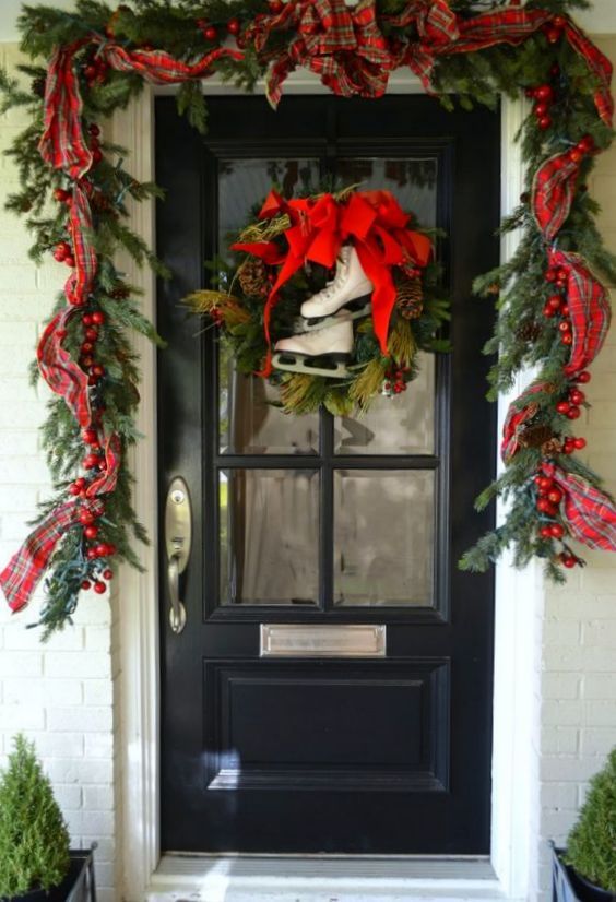 a bright Christmas porch with an evergreen garland with berries, plaid ribbons, a wreath with a red bow and skates