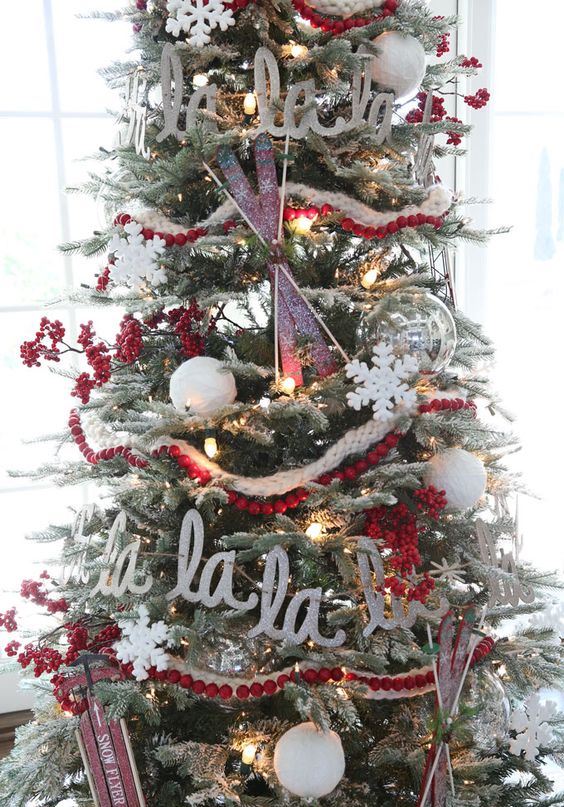 A flocked Christmas tree with lights, cranberry garlands, letters, skis and sleighs is a chic vintage inspired idea