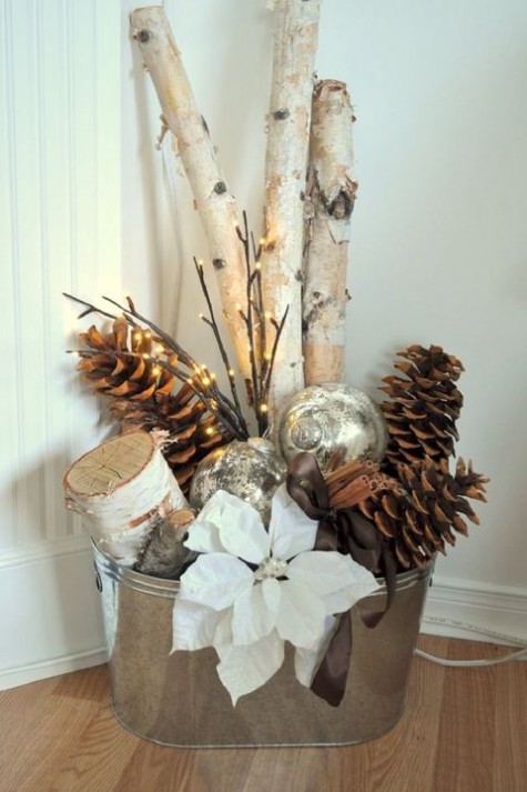 a galvanized bathtub with large pinecones, firewood, lights, ornaments and a fabric flower for Christmas decor