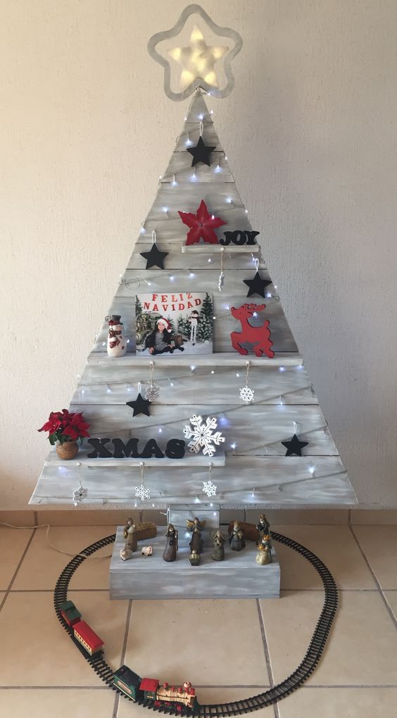 a grey rustic Christmas tree with shelves, stars, lights, letters, blooms and deer decorations