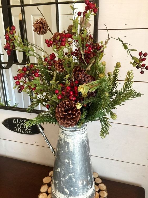 a metal jug with evergreens, pinecones, berries and greenery is a cool Christmas centerpiece