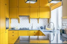 a mustard kitchen with grey stone countertops and grey stools, a white subway tile backsplash anbd geometric pendant lamps