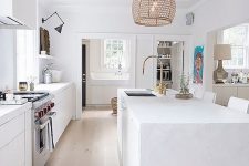 a pure white kitchen is given a rustic and outdoor feel with rattan lampshades over the kitchen island