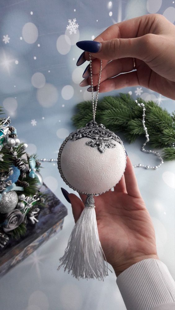 A refined vintage inspired white snowball Christmas ornament with embellishments and a large tassel is wow