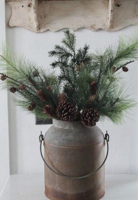 a rustic Christmas decoration of an old milk churn with evergreens with pinecones can be placed inside or outside