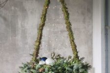 a rustic Christmas tree wrapped wiht moss, with lights and evergreens, pinecones, ornaments for a cozy and modern feel