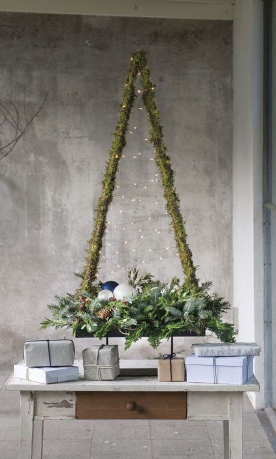 a rustic Christmas tree wrapped wiht moss, with lights and evergreens, pinecones, ornaments for a cozy and modern feel