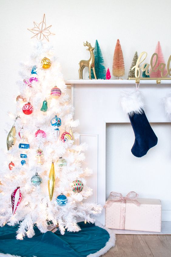 a white Christmas tree decorated with colorful vintage Christmas ornaments and a topper is a stylish and chic idea