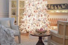 a white lit up Christmas tree with white, silver, gold and pink ornaments, white chairs with white faux fur blankets are amazing